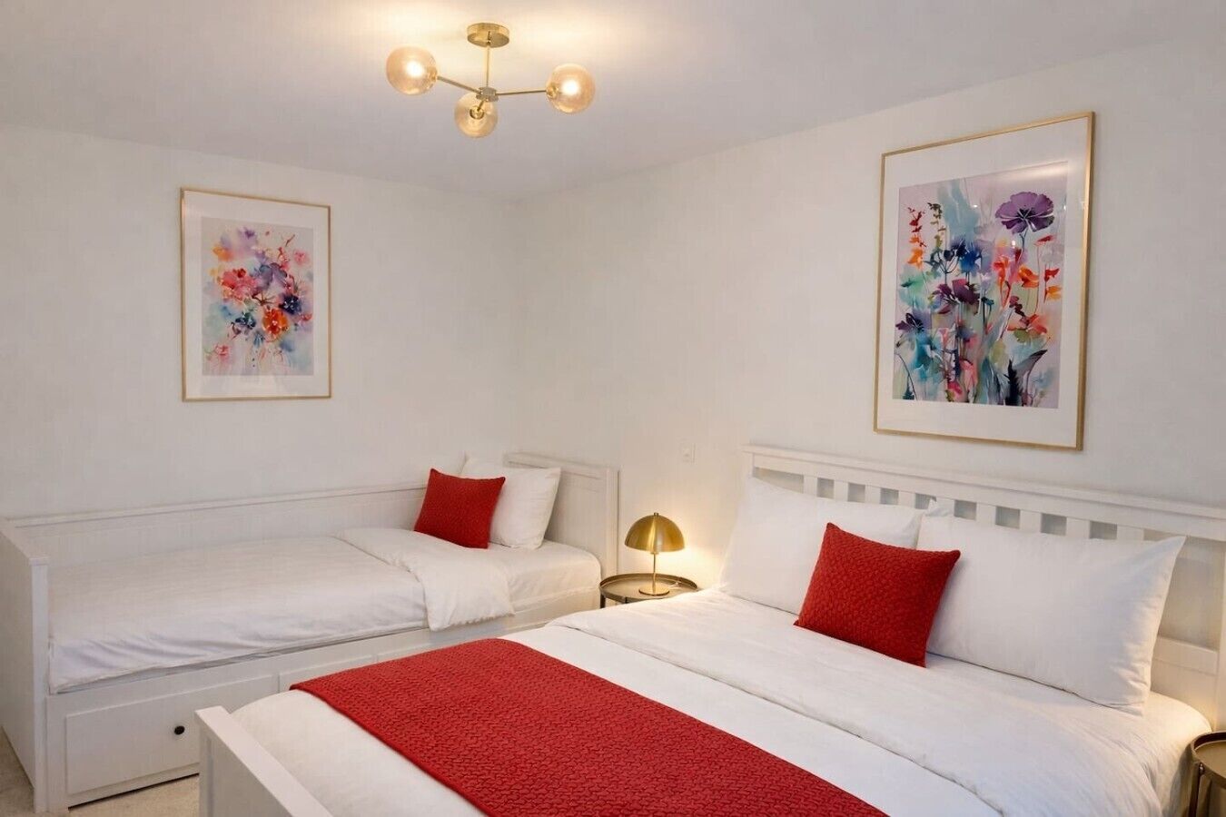 Et hotelværelse med to senge, et rødt tæppe og to blomsterbilleder i rammer på væggene.