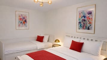 Et hotelværelse med to senge, et rødt tæppe og to blomsterbilleder i rammer på væggene.