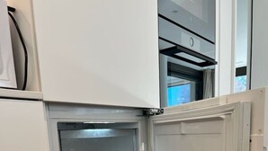 Une cuisine équipée d’un four encastré et d’un réfrigérateur blanc.