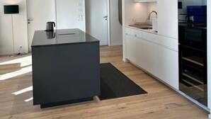 Une cuisine moderne dotée d’un îlot central, de meubles blancs et d’appareils électroménagers intégrés.