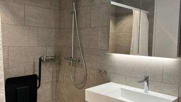 A modern bathroom with a shower, a sink, and a mirror.