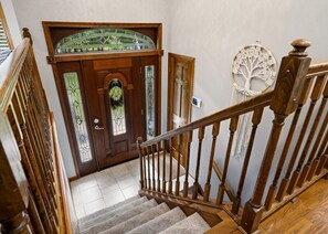 A wooden staircase with a handrail, a wooden door with a glass panel, and a wall-mounted macrame tree decoration. - Hot Tub + Sauna | Game Room | 6mi to Camelback (Stroudsburg)