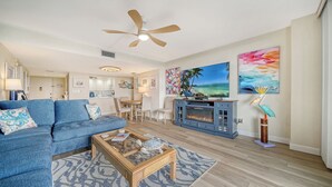 A living room with a blue sofa, a coffee table, a fireplace, and a TV. - 🏝️☀️🎏 Pool, Pickle, Tennis, Beach Access all at Sun-Drenched Siesta Key Getaway⛱️🌞🐬 (Siesta Key)