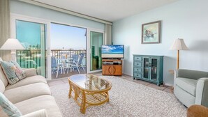 Ein geräumiges Wohnzimmer mit Balkon, einem Fernseher, einem Sofa, einem Couchtisch und einem Schrank.
