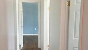 Un couloir étroit avec un plancher en bois et des murs blancs.