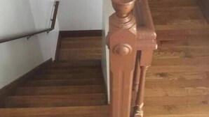 Un escalier en bois, doté d’une main courante en bois et d’une main courante en métal sur le côté gauche.