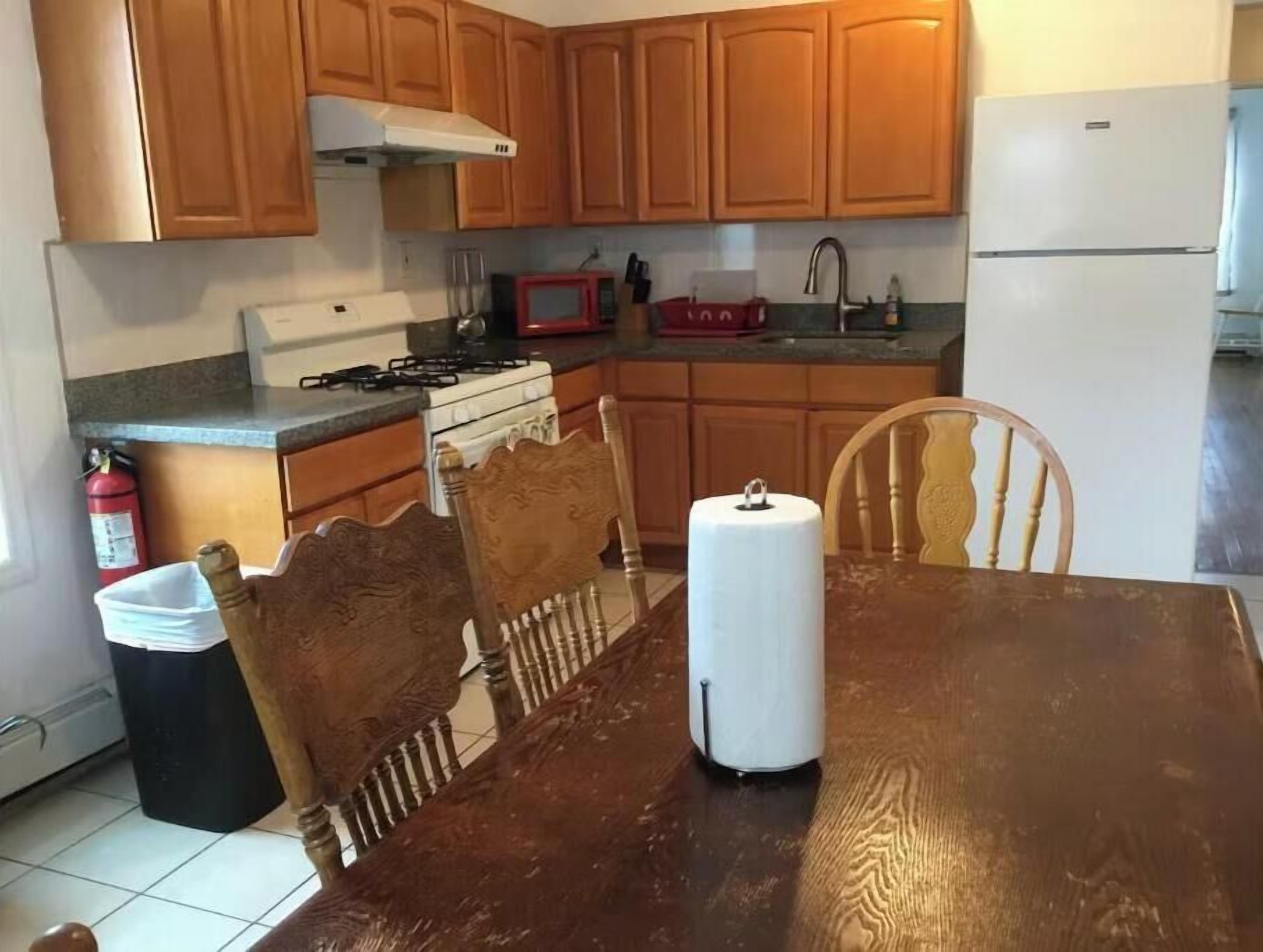 A kitchen with wooden cabinets, a gas stove, a microwave, and a refrigerator.