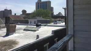 Un toit-terrasse avec une surface plane, une cheminée et un grand bâtiment en arrière-plan.