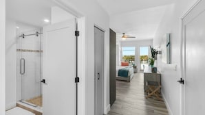 Una habitación de hotel moderna con ducha, cama, escritorio y vistas al exterior.