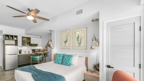Una habitación de hotel moderna con cama, escritorio, kitchenette y ventilador de techo.
