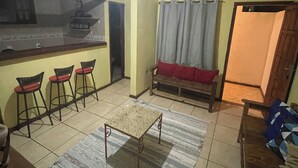 Ein kompakter Wohnbereich mit Küchenzeile, Esstisch, Sofa und einem gemusterten Teppich.