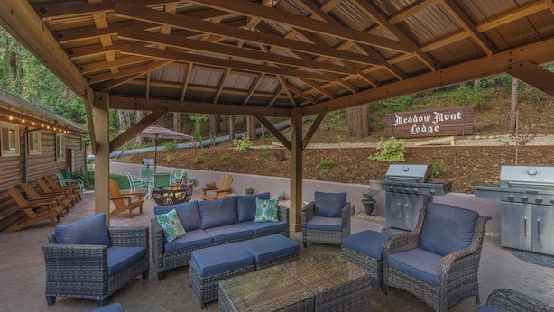 An outdoor patio area with wicker furniture, a grill, and a sign reading "Meadow Mont Lodge". - Comfortable Lodge Room 13 with Extra Amenities (2 doubles, pet-friendly) (Arnold)