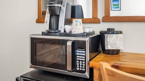 A microwave with a coffee maker and a disposable cup on top. - Comfortable Lodge Room 13 with Extra Amenities (2 doubles, pet-friendly) (Arnold)
