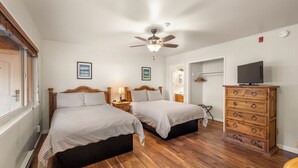 A bedroom with two beds, a ceiling fan, a wooden dresser, and a television. - Comfortable Lodge Room 12 with Extra Amenities (2 doubles, no pets) (Arnold)