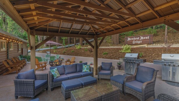 An outdoor patio area with wicker furniture, a grill, and a sign reading "Meadow Mont Lodge". - Comfortable Lodge Room 12 with Extra Amenities (2 doubles, no pets) (Arnold)