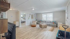 Ein geräumiges Wohnzimmer mit einem grauen Sofa, einem Holztisch und einem Fernseher.