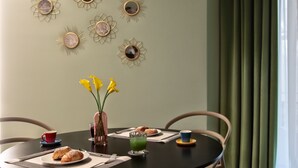 Ein Esstisch mit einer Vase gelber Blumen, einem Glas grünen Saftes und Croissants.