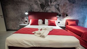 Hotellihuone, jossa on suuri sänky, punaiset vuodevaatteet ja pääty.