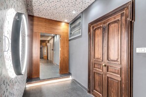 Ein Flur mit einer Holztür, einem Spiegel und einer Wand mit Muster.