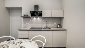 Cozinha compacta com fogão embutido, pia e chaleira sobre a bancada.