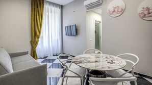 Uma sala de estar moderna com um sofá, uma mesa de jantar com cadeiras, uma TV de tela plana e um ar-condicionado.