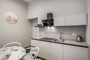 A compact kitchen with a sink, a kettle, and a decorative plate on the wall. - Golden Rose - One Bedroom Apartment, Sleeps 5 (Naples)