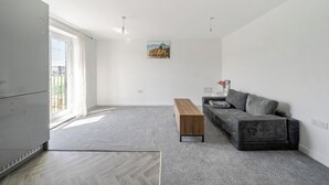 En moderne stue med en grå sofa, et træbord og et billede på væggen.