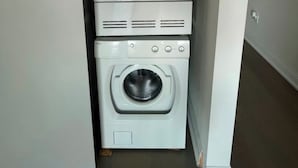 A laundry room with stacked appliances including a dryer, washer, and stacked washer-dryer unit.