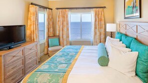 Ein Hotelzimmer mit Bett, Fernseher, Sessel und Meerblick.
