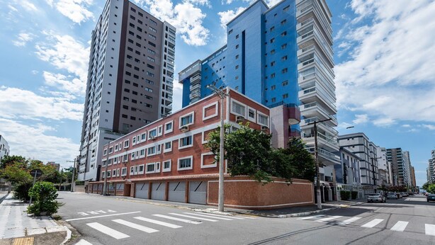 Una calle urbana moderna con edificios altos, un paso de peatones y cielo despejado.