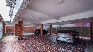 Un área de estacionamiento techada con dos coches, piso de ladrillo y pared de azulejos.