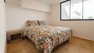 Un dormitorio con cama, mesita de noche, armario empotrado y ventana.