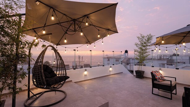Eine Dachterrasse mit Hängesessel, Polstersessel und Lichterkette.