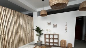 Ein modernes Wohnzimmer mit einer Wand aus Holzlatten, einem Couchtisch mit Kuchen, weißen Kissen und hängenden Gewebeleuchten.