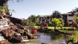 Een hotel met een zwembad, omringd door tropische planten en een waterval.