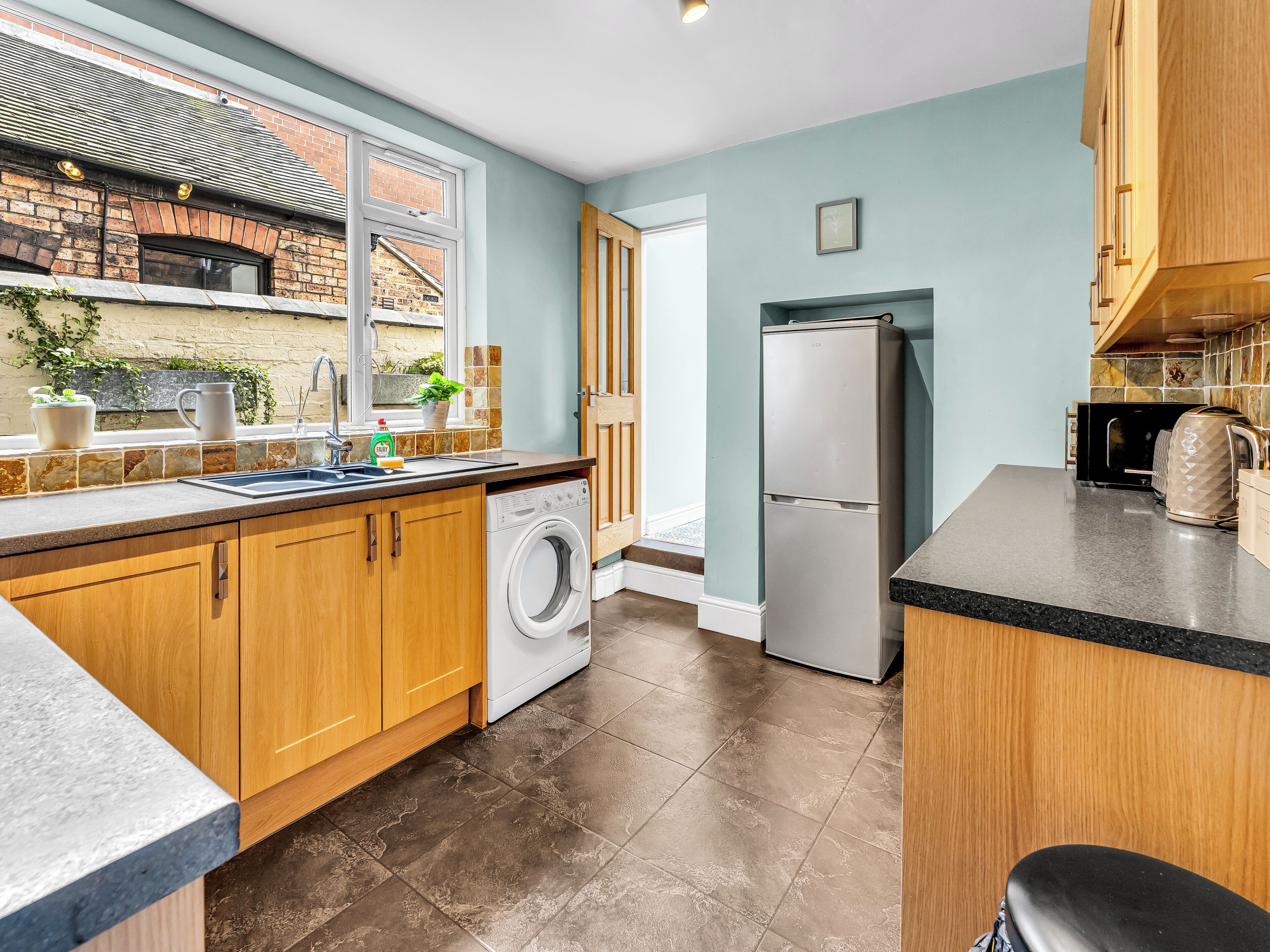 A modern kitchen with a washing machine, a refrigerator, and a sink.