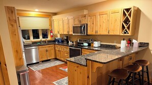 A kitchen with wooden cabinets, a granite countertop, a microwave, and a wine rack.