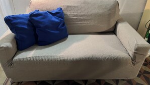Un sofá color beige con un estampado geométrico, acompañado por dos almohadas azules.
