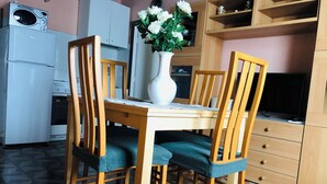 Una cocina con una mesa de comedor, sillas, un microondas, una estufa y un florero con flores.