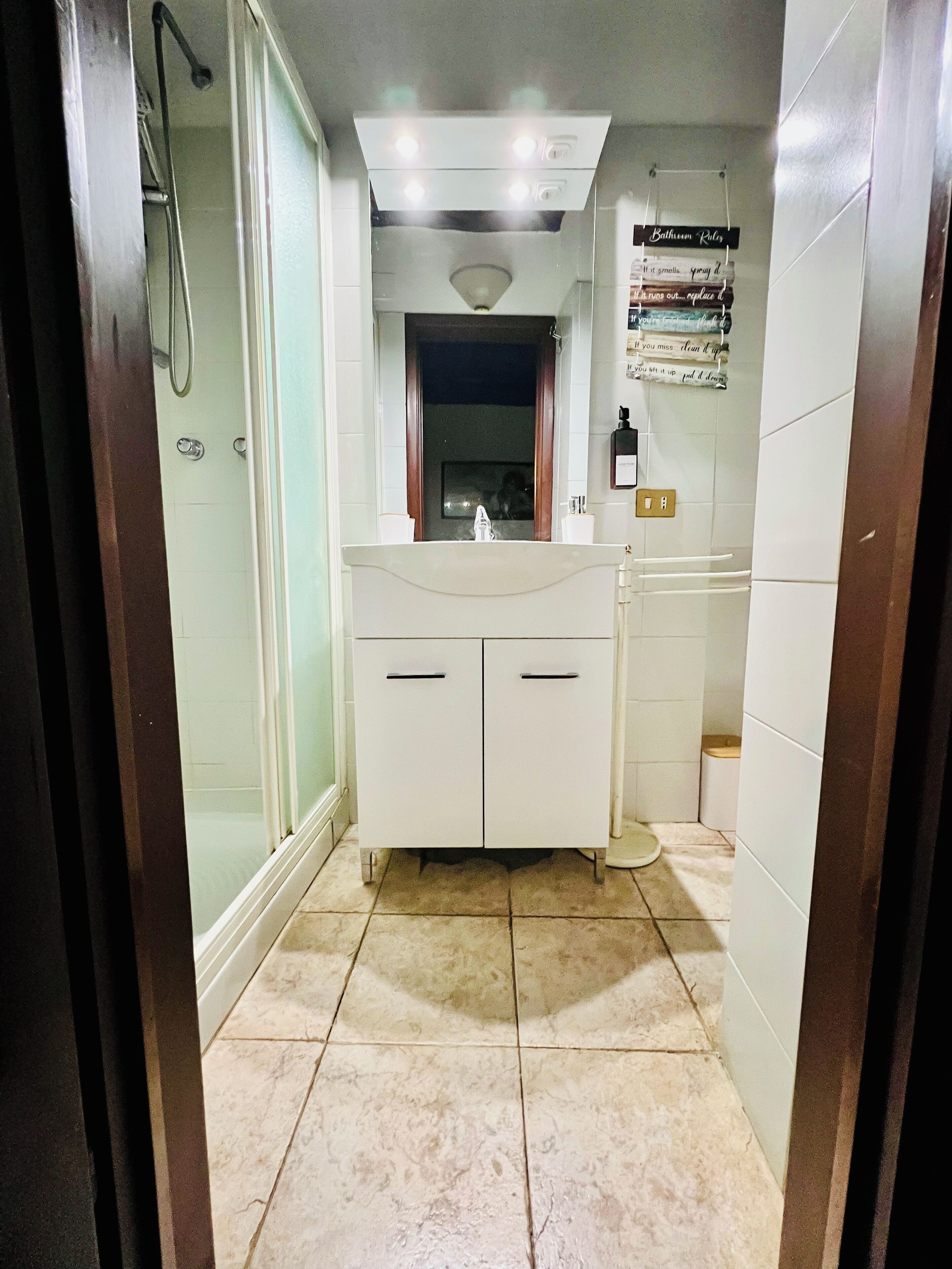 A bathroom with a white vanity, a mirror, and a shower area.