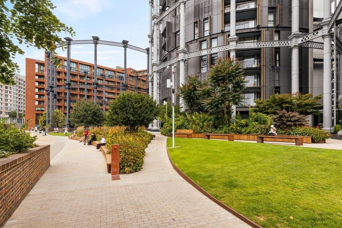 A modern urban building complex with a central courtyard, paved pathways, and greenery.