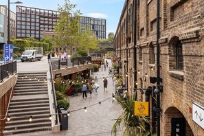 A pedestrian street with outdoor seating, a vintage clothing store, and a staircase leading to an upper level. - Modern Vibes + Prime Location – 2BR by Kings Cross (Greater London)