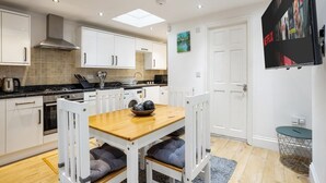 Een moderne keuken met witte kasten, een houten eettafel en een zwart-wit poster aan de muur.