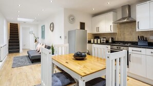 Een moderne keuken met witte kastjes, een roestvrijstalen afzuigkap en een zwart aanrecht.