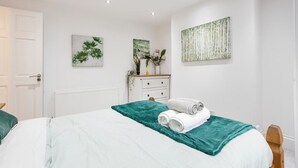 Een slaapkamer met een bed, een dressoir en wanddecoratie.