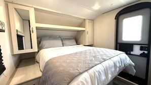 Quarto compacto com cama, guarda-roupa e janela.
