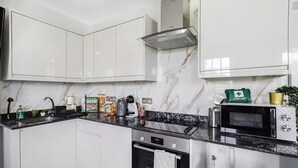 Cozinha moderna com armários brancos, bancada preta, forno embutido e micro-ondas.