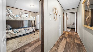 A compact, modern RV interior with a bunk bed, a small ladder, and a wooden floor. - Joy Drive In Movie & RV Resort - 2995 Barr Ln - Relaxing 3BR/2BA Getaway (Copperas Cove)