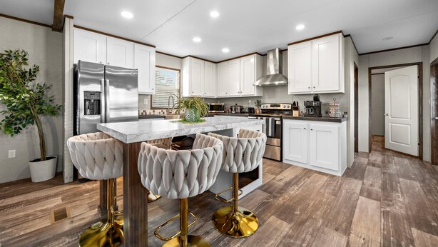 A modern kitchen with white cabinets, stainless steel appliances, and a marble island. There are two bar stools with gold legs and a potted plant on the island. - Joy Drive In Movie & RV Resort - 2995 Barr Ln - Relaxing 3BR/2BA Getaway (Copperas Cove)