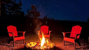 A campfire with three red Adirondack chairs around it, set on a gravel surface under a starry night sky. - Joy Drive In Movie & RV Resort - 2995 Barr Ln - Relaxing 3BR/2BA Getaway (Copperas Cove)